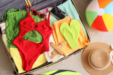 Elbiseli bavulu aç ve plaj topu halıda, üst manzara