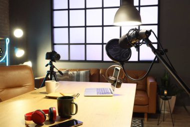 Podcaster 'ın iş yeri. Laptop, mikrofon ve karanlık stüdyoda parlayan lambalar.