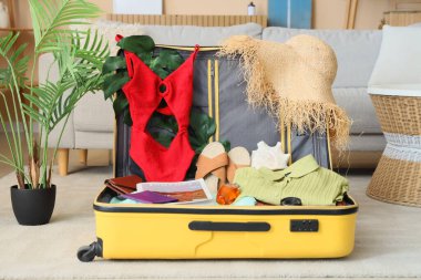 Oturma odasında plaj aksesuarlarıyla dolu bavulu aç.