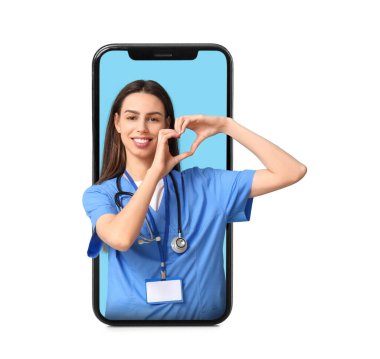 Genç bayan doktor mavi arka planda kalp hareketi yapıyor.