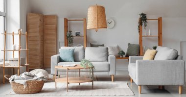 Işıl ışıl oturma odasının içi rahat gri koltuklar ve ahşap kahve masası.