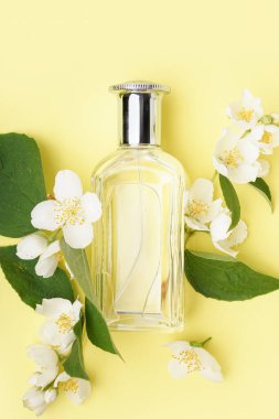 Parfüm şişesi ve sarı arka planda güzel yasemin çiçekleri olan kompozisyon