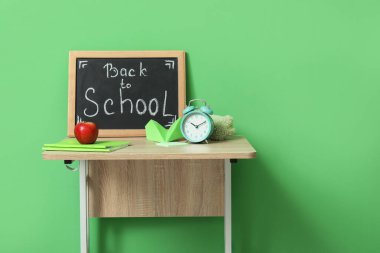 Modern okul masası, kırtasiye ve karatahta ile yeşil duvarın yanındaki odada okula dönüş metni