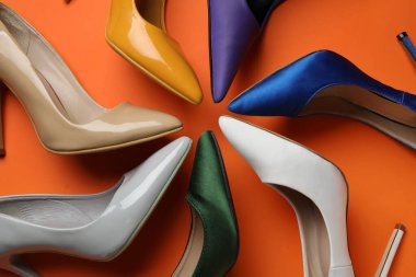 Turuncu arka planda farklı yüksek topuklu ayakkabılar.