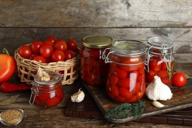 Kavanozlar dolusu domates turşusu ve ahşap arka planda farklı baharatlar.