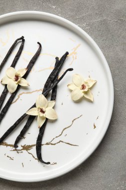 Aromatik vanilyalı tabaklar ve gri arka planda çiçekler.