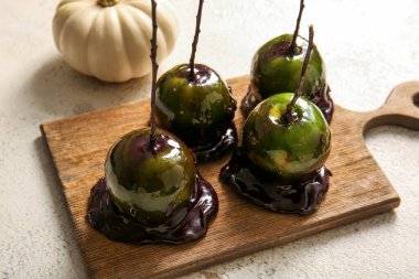 Beyaz arka planda Cadılar Bayramı için lezzetli karamelli elma tahtası.