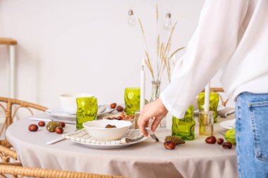 Şükran Günü yemeği için yemek masasını dekore eden kadın.