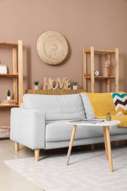 Gri kanepesi, masası ve raf ünitesi olan şık bir oturma odası.