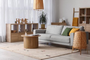 Gri kanepesi, ahşap masası ve lambaları olan rahat bir oturma odası.