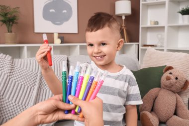 Sevimli küçük çocuk annesinden keçeli kalem alıyor.