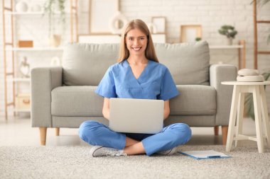 Kadın stajyer, oturma odasında dizüstü bilgisayarla ders çalışıyor.