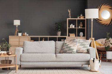 Gri kanepesi, lambaları ve raf ünitesi olan modern oturma odasının içinde.