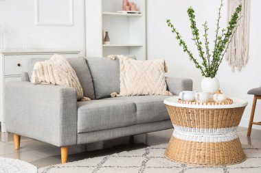 Rahat bir kanepe, sehpa ve vazo, güzel oturma odasında çiçek açan dallar.