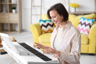 Evde sentezleyici çalan genç bir kadın.