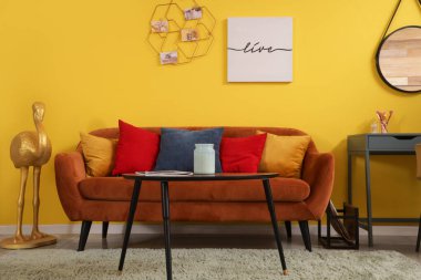 Duvarında kahverengi kanepe, sehpa ve ruh hali tahtası asılı şık bir oturma odası.