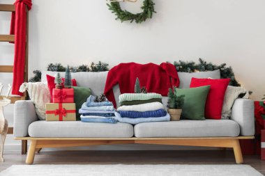 Kış kıyafetleri, Noel süsleri ve evdeki kanepede hediye kutuları.