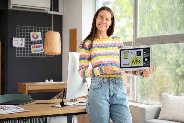 Dizüstü bilgisayarı olan genç bir bayan grafik tasarımcısı.