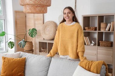 Gri kanepede uzanan genç ve güzel bir kadın.