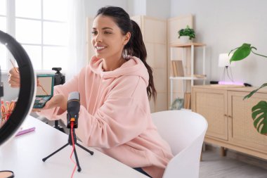 Female beauty blogger with eyeshadows recording video at home
