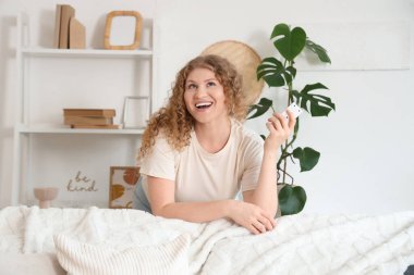 Evinde klimalı uzaktan kumandalı gülümseyen genç bir kadın. Yakın çekim.