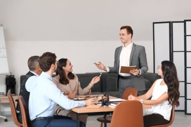 Not defteri olan bir erkek avukat ve ofiste çalışan iş arkadaşları.