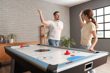 Genç arkadaşlar evlerinde hokey oynarken birbirlerine beşlik çakıyorlar.