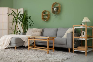 Oturma odasının iç tarafında rahat bir kanepe, çiçek ve kahve masası.