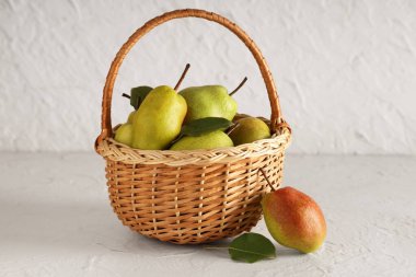 Beyaz arka planda tatlı olgun armutlarla dolu bir sepet.