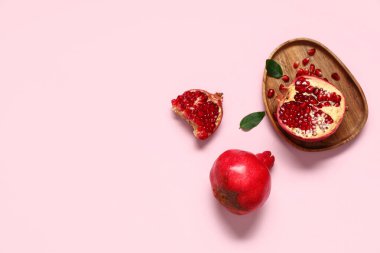 Tahta tepsi taze olgun nar ve pembe arka planda tohumlar.