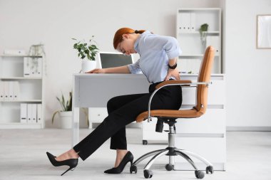 Güzel genç iş kadını koltukta sırt ağrısı çekiyor.