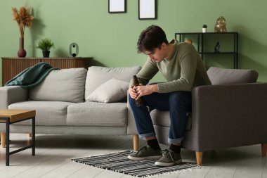 Evdeki kanepede oturan bunalımlı genç adam.