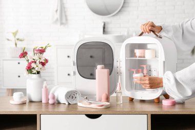 Kozmetik ürünleri için küçük buzdolabından krema alan kadın eller. Yakın çekim.