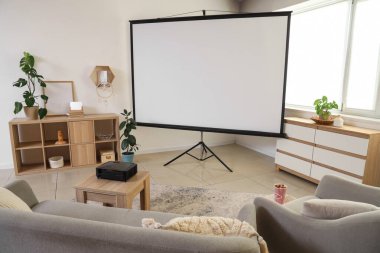 Gri kanepesi ve kahve masasında modern projektörü olan şık bir oturma odası.