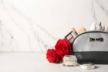 Makyaj ürünleri ve beyaz arka planda kırmızı güller olan kozmetik çanta. Sevgililer Günü kutlaması