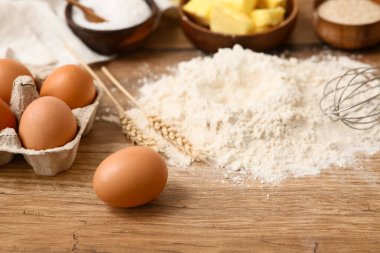 Tahta zemin üzerinde hamur hazırlamak için yumurta ve buğday dikenli un yığını.