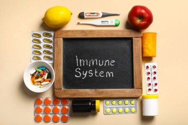 IMMUNE SİSTEM yazılı tebeşir tahtası, farklı haplar, termometreler ve renk arkaplanlı meyveler