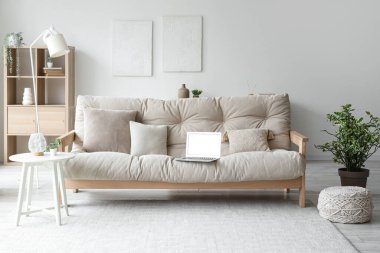 Oturma odasının içi boş dizüstü bilgisayarlı kanepe, masa ve bitkilerle dolu.