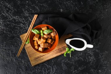 Siyah arka planda kızarmış tofu peyniri ve fesleğen ile kase