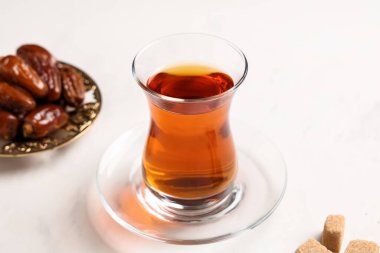 Bir bardak şekerli Türk çayı ve beyaz arka planda kurutulmuş hurma.