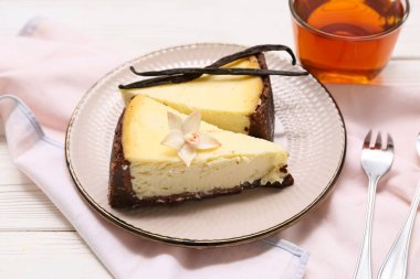 Bir tabak vanilyalı cheesecake ve beyaz ahşap zemin üzerinde bir bardak çay.