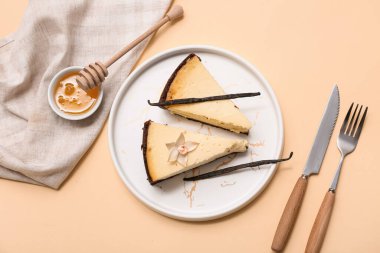 Tatlı vanilyalı peynirli kek ve bej arka planda bir kase bal.