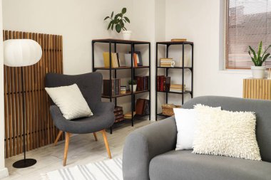 Koltuğu, koltuğu ve kitaplığı olan aydınlık oturma odasının içinde.