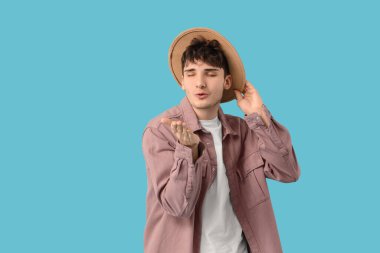 Yakışıklı genç adam mavi arka planda öpüşüyor.