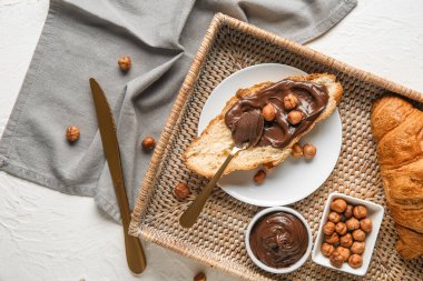 Çikolata kaplı bir tabak tatlı kruvasan ve beyaz arka planda fındık.