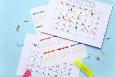 Mavi arka planda işaretleyiciler, iğneler ve ataçlarla takvim. Planlama kavramı