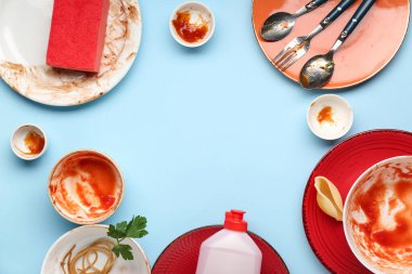 Bir sürü kirli tabak, çatal bıçak, sünger ve deterjandan yapılmış çerçeve mavi arka planda.
