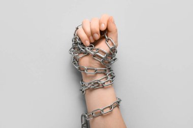 Gri arka planda sıkılmış yumrukları ve zincirleri olan bir el. Zulüm kavramı