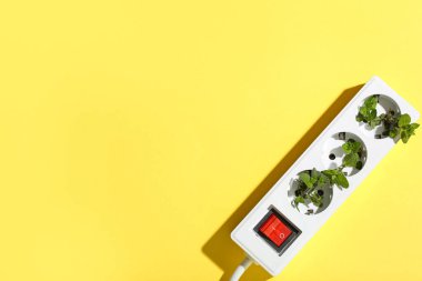 Sarı arka planda yaprakları olan çoklu soket. Yeşil teknoloji kavramı