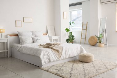 Rahat yataklı, komodinli ve çiçekli aydınlık yatak odasının içi.